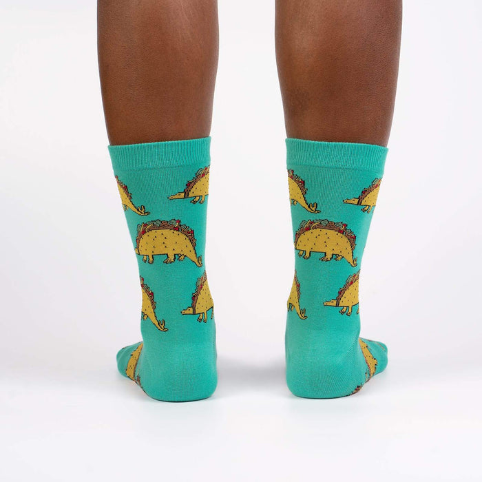 A pair of green socks with a pattern of tacosaurus, a dinosaur with a taco shell for a body.