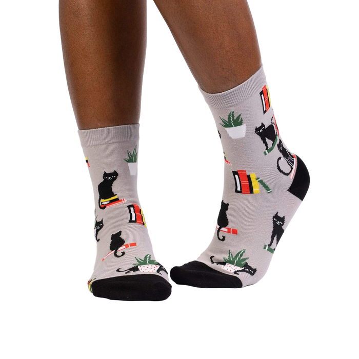 Lifestyle shot of model wearing 'Booked For Meow' socks, showcasing how they look on feet.
