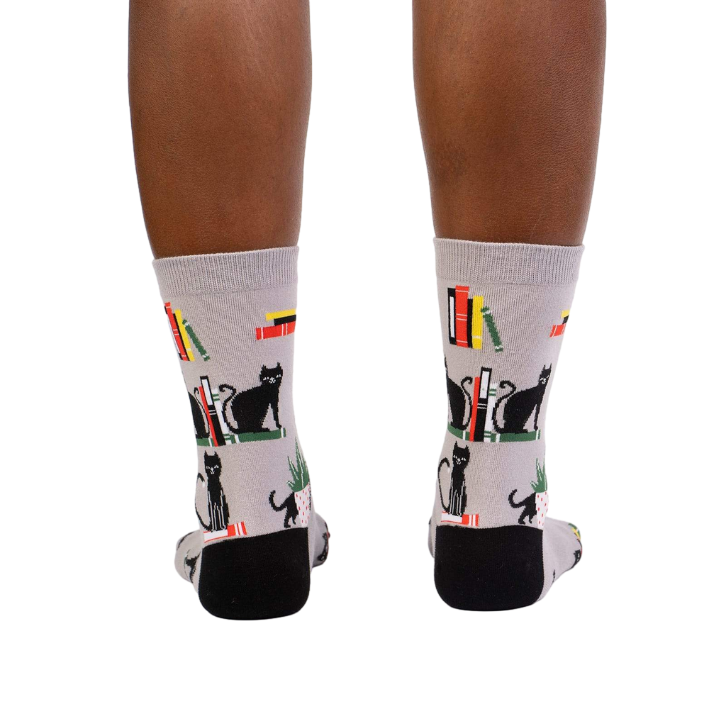 Rear view of model's legs wearing 'Booked For Meow' socks.