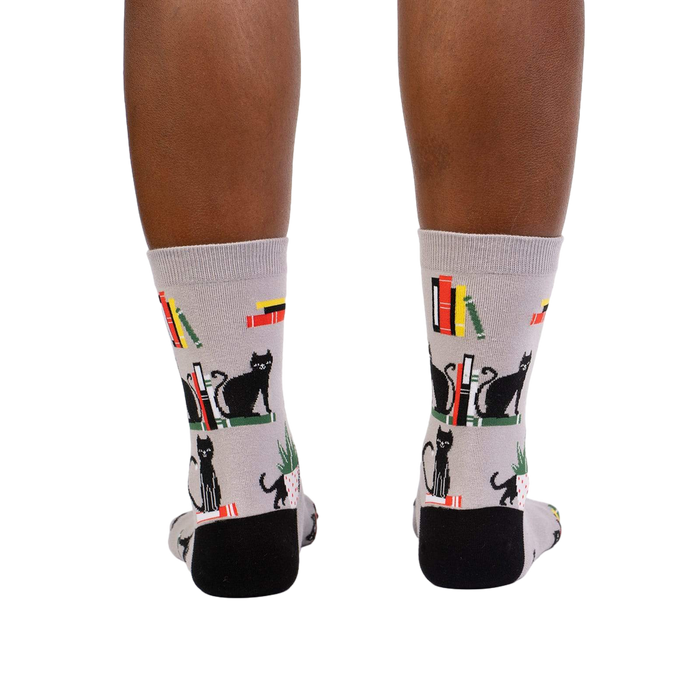 Rear view of model's legs wearing 'Booked For Meow' socks.