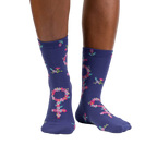 Lifestyle shot: A person's legs wearing the purple floral Venus symbol crew socks against a white background.