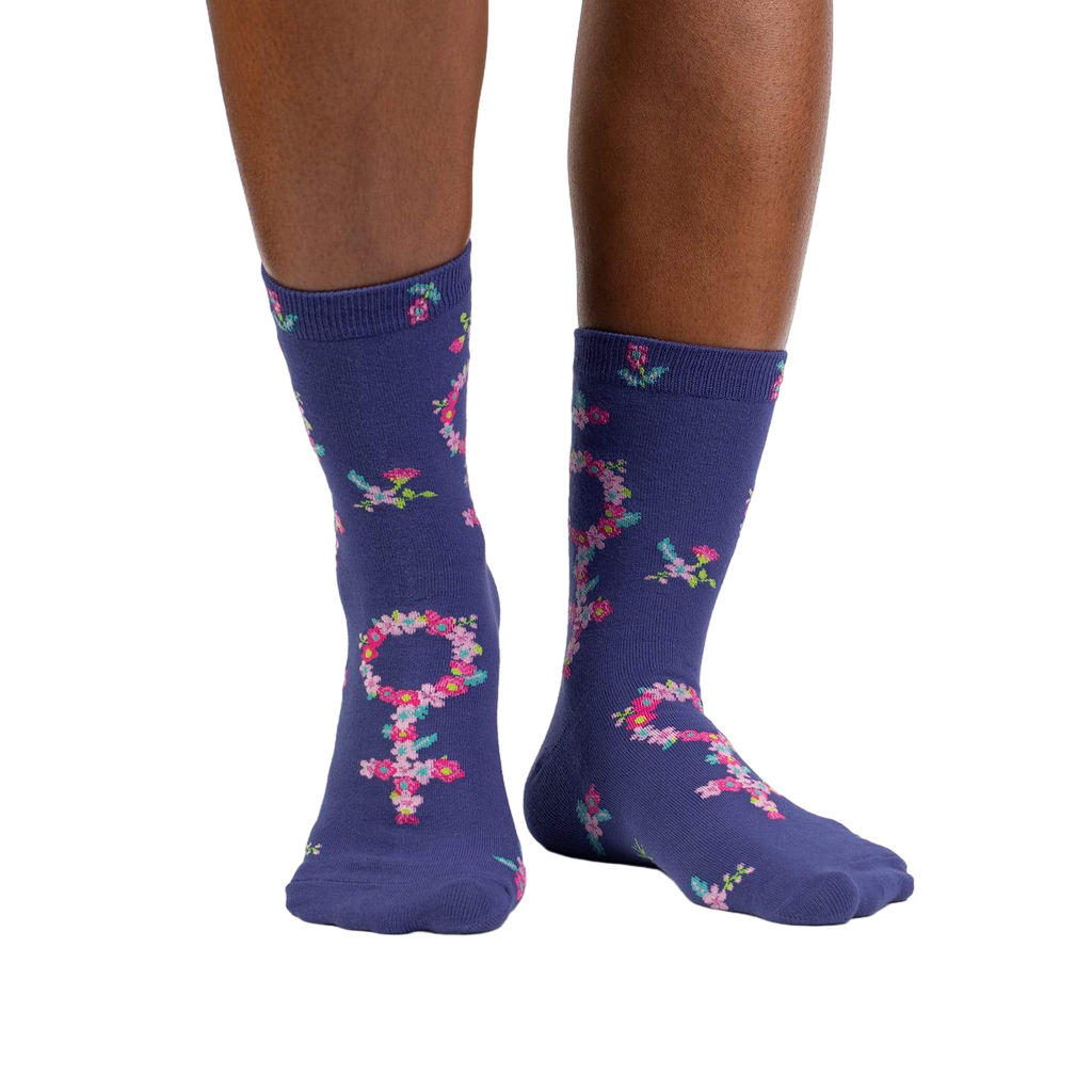 Lifestyle shot: A person's legs wearing the purple floral Venus symbol crew socks against a white background.
