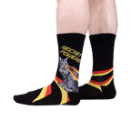 Lifestyle shot showing the 'Secret Powers' socks on a person's legs. The socks are predominantly black with yellow and red stripes.