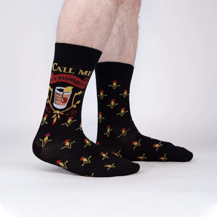 A pair of black socks with a pattern of red and yellow fleur-de-lis and the words 