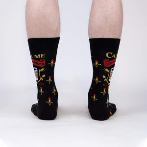 A pair of black socks with a pattern of red and yellow fleur-de-lis and the words 