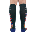 Rear view of the socks showing the design on the back of the legs.  These are dark green knee-high socks with a book stack design.
