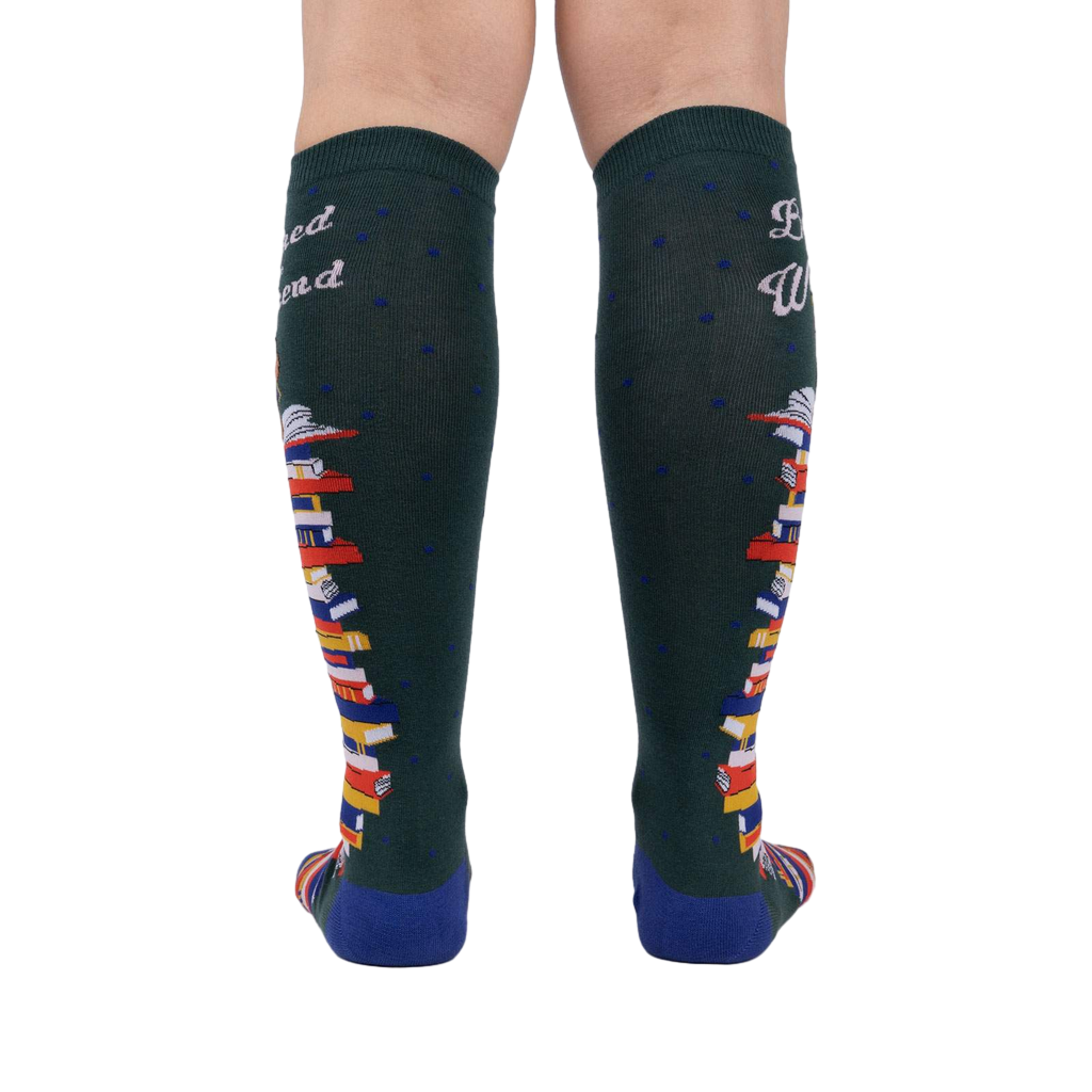 Rear view of the socks showing the design on the back of the legs.  These are dark green knee-high socks with a book stack design.