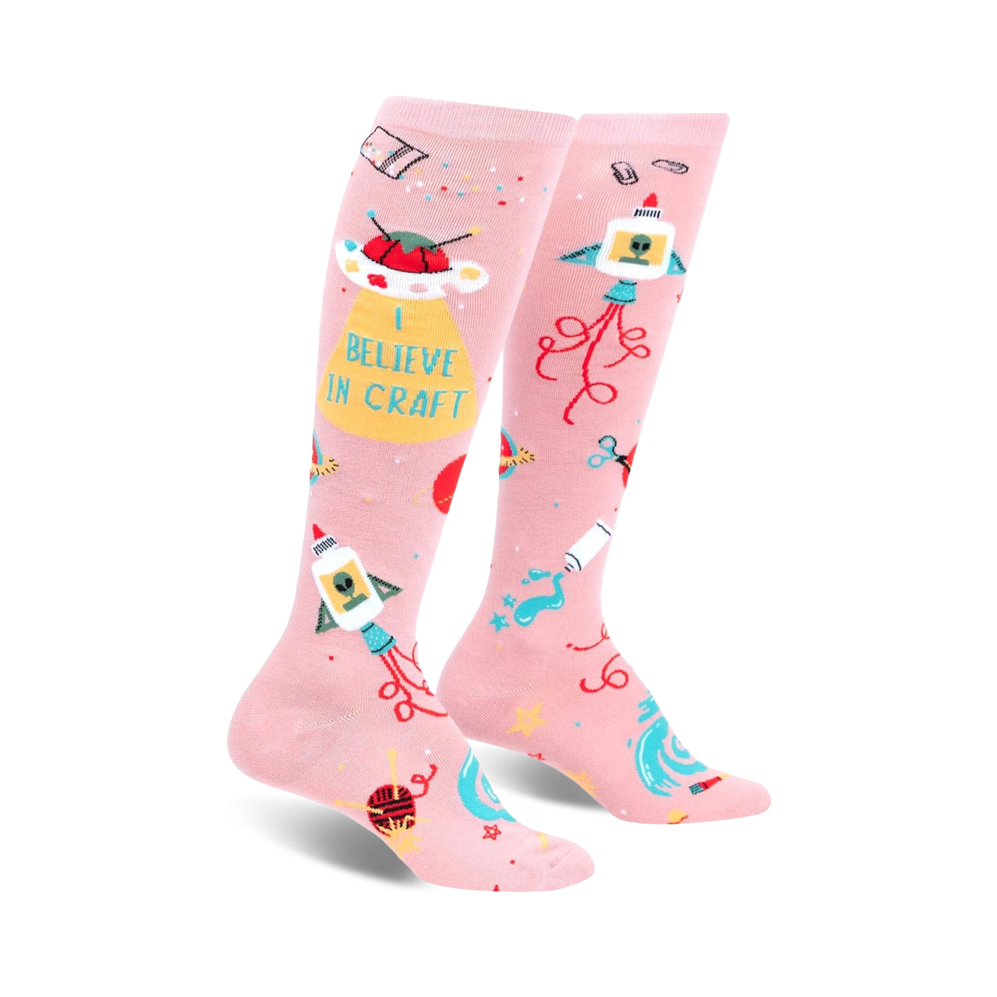 Pair of pink knee-high socks with a fun design featuring rockets, UFOs, crafting icons, and the text 'I Believe In Craft'.