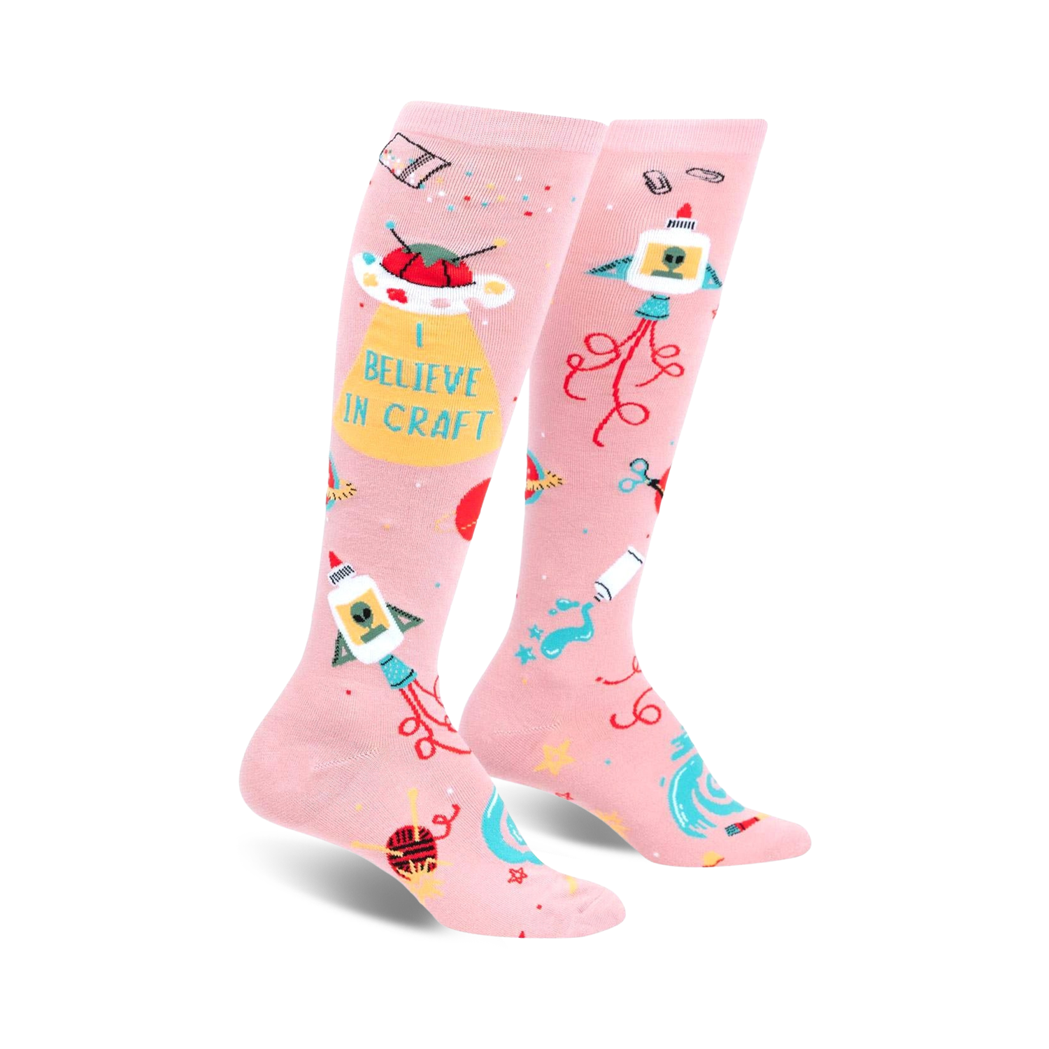 Pair of pink knee-high socks with a fun design featuring rockets, UFOs, crafting icons, and the text 'I Believe In Craft'.