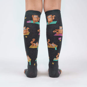 A pair of gray knee-high socks with a pattern of cartoon red pandas doing yoga.