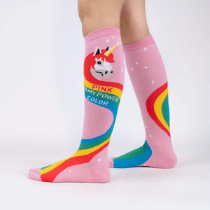 A pair of pink knee-high socks with a rainbow and unicorn pattern. The socks have the words 