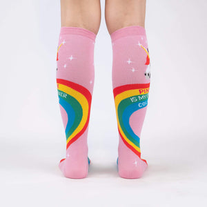 A pair of pink knee-high socks with a rainbow and unicorn pattern. The socks have the words 