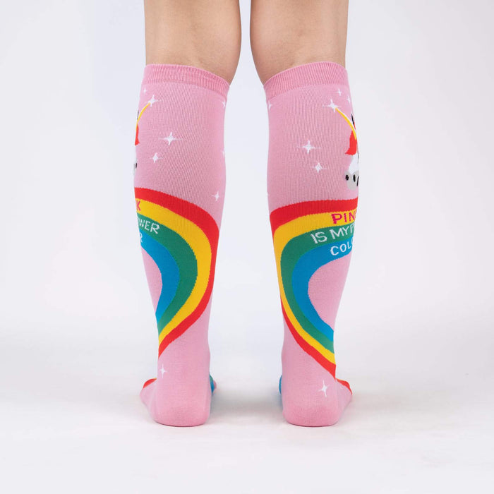 A pair of pink knee-high socks with a rainbow and unicorn pattern. The socks have the words 