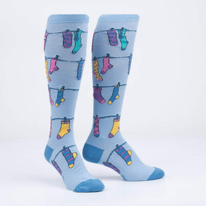 A pair of blue knee-high socks with a pattern of colorful socks hanging on a clothesline.
