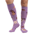 Lifestyle photo showcasing the lavender purple knee-high socks with dog illustrations on a person's legs.