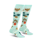 Pair of light teal knee-high socks featuring hens, chicks, and potted plants in a whimsical design.