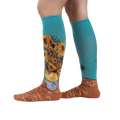 Lifestyle shot showing the socks on a person's legs.  The socks are teal with sunflowers.