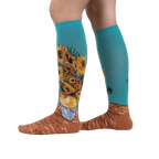 Lifestyle shot showing the socks on a person's legs.  The socks are teal with sunflowers.