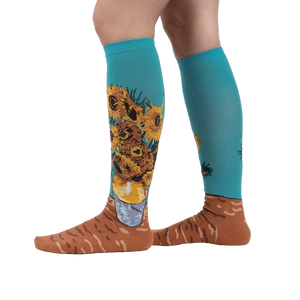 Lifestyle shot showing the socks on a person's legs.  The socks are teal with sunflowers.