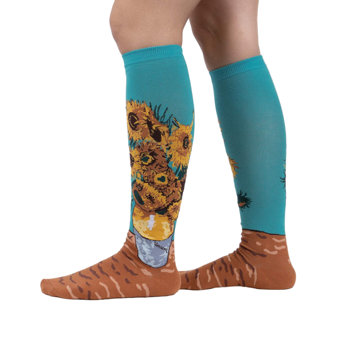Lifestyle shot showing the socks on a person's legs.  The socks are teal with sunflowers.
