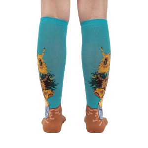 Rear view of the sunflower socks on a person's legs against a white background. The teal and sunflower design is clearly visible.