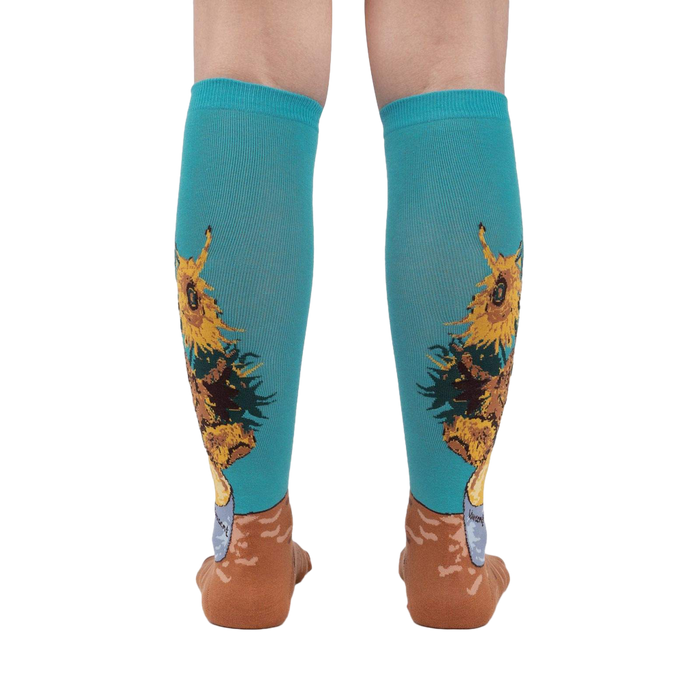 Rear view of the sunflower socks on a person's legs against a white background. The teal and sunflower design is clearly visible.
