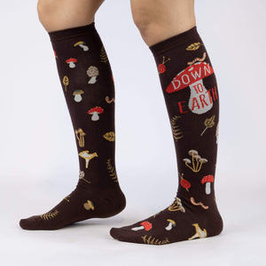 A pair of brown knee-high socks with a pattern of red mushrooms, green leaves, and orange snails.