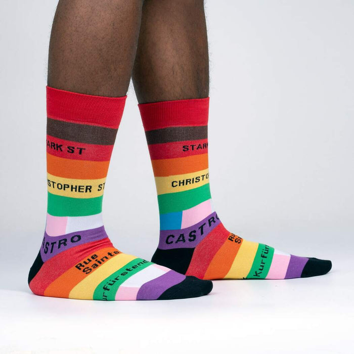 A person is modeling a pair of rainbow socks with the words 