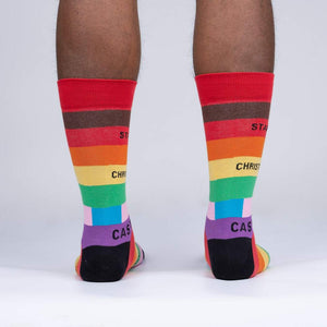 A person is modeling a pair of rainbow socks with the words 