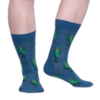 Lifestyle shot of model wearing a pair of blue crew socks with a fun pickle pattern.