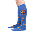 Lifestyle shot of Rise and Shine knee-high socks on a person's legs against a black background.