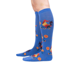 Lifestyle shot of Rise and Shine knee-high socks on a person's legs against a black background.