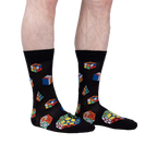 Lifestyle shot showing a person's legs wearing the Puzzle Box socks. The socks are black with colorful Rubik's Cube and geometric designs.