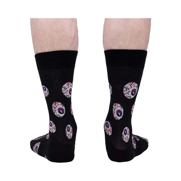 Rear view of a pair of black crew socks with an eyeball pattern.