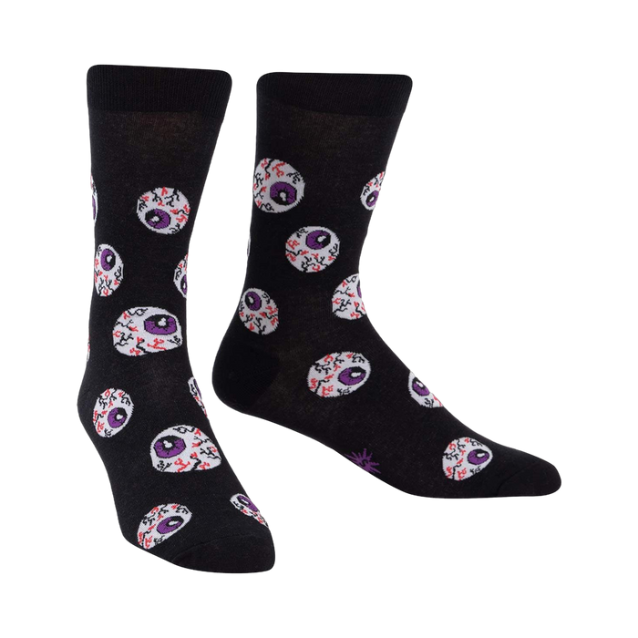 Black crew socks with a repeating pattern of purple and red eyeball designs. The socks glow in the dark.
