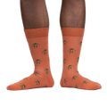 Lifestyle shot of a person wearing terracotta crew socks with a bee pattern.