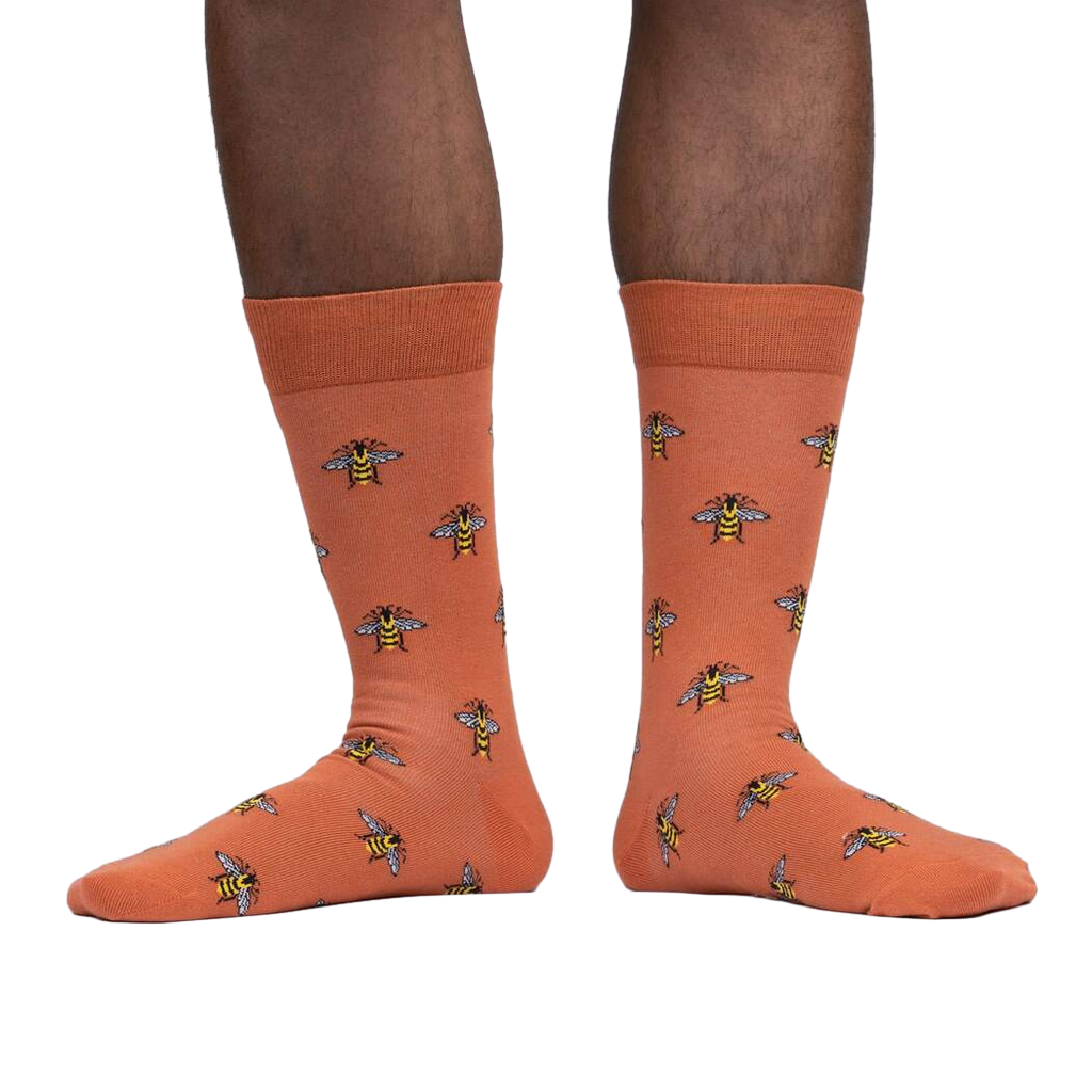 Lifestyle shot of a person wearing terracotta crew socks with a bee pattern.