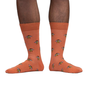 Lifestyle shot of a person wearing terracotta crew socks with a bee pattern.