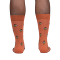 Rear view of a person wearing terracotta crew socks with a bee pattern.
