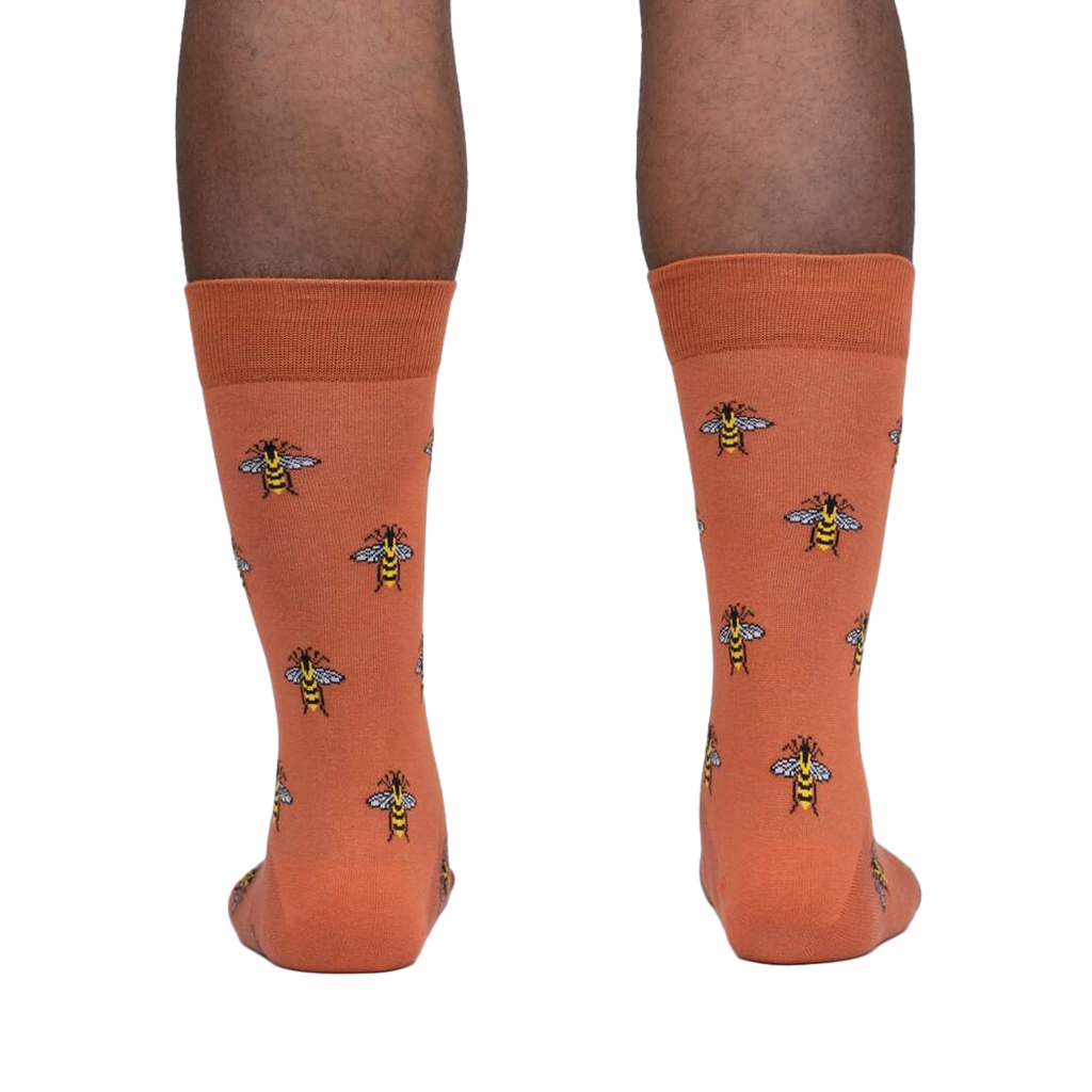 Rear view of a person wearing terracotta crew socks with a bee pattern.