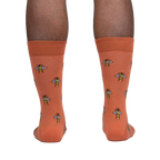 Rear view of a person wearing terracotta crew socks with a bee pattern.