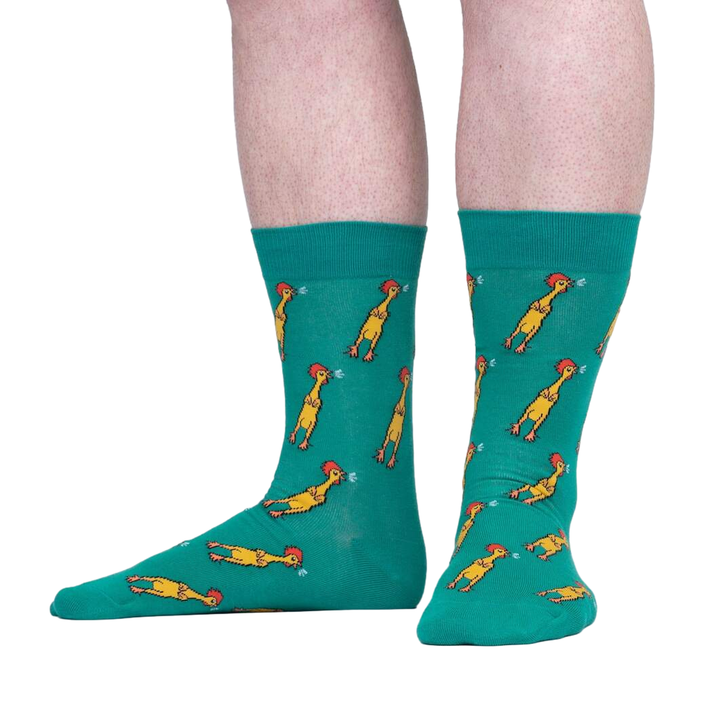 Lifestyle shot of a person wearing teal crew socks with a chicken pattern. The socks are shown from the knees down.