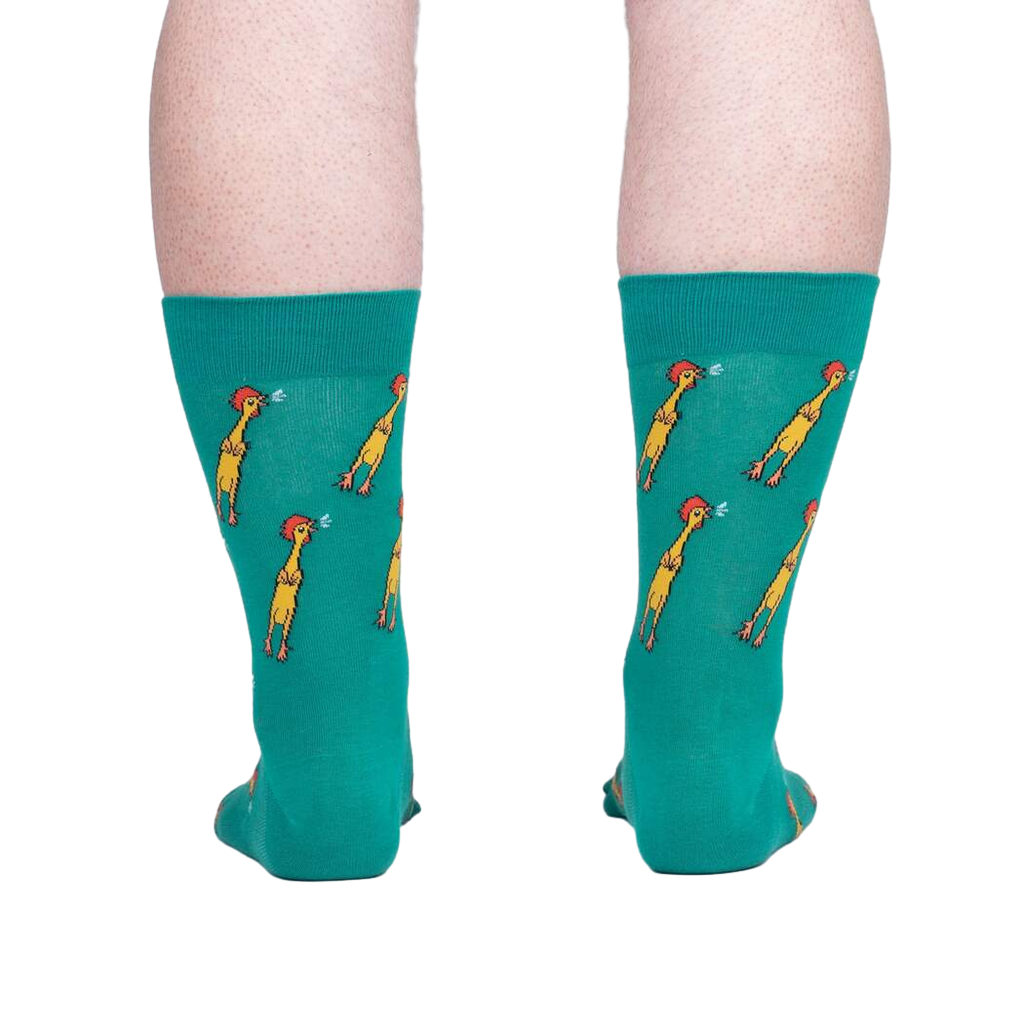 Rear view of teal crew socks with a repeating pattern of yellow chickens, showcased against a neutral gray background.