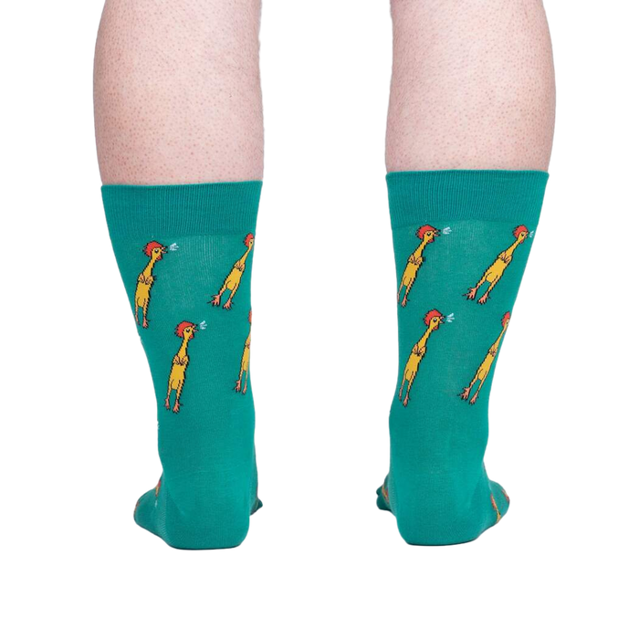 Rear view of teal crew socks with a repeating pattern of yellow chickens, showcased against a neutral gray background.