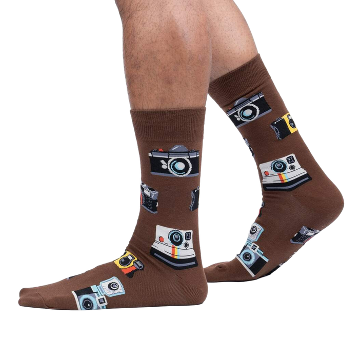 Lifestyle shot showing brown camera socks on a person's legs against a white background.