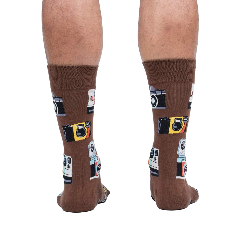 Rear view of a person wearing brown crew socks with a retro camera print.