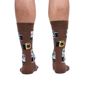 Rear view of a person wearing brown crew socks with a retro camera print.