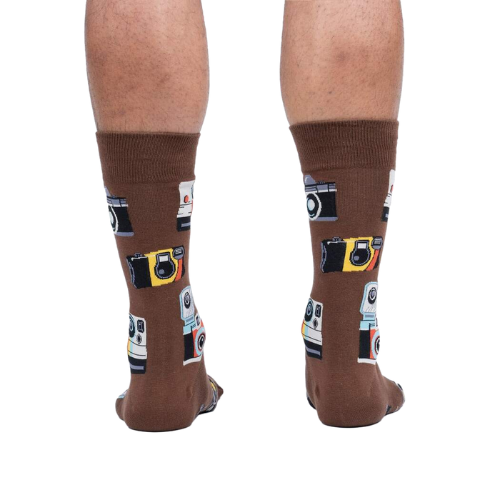 Rear view of a person wearing brown crew socks with a retro camera print.