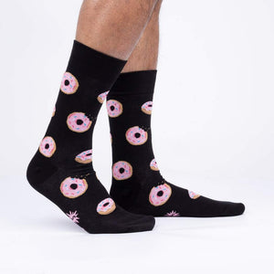 A pair of black socks with a pattern of pink donuts with blue, white, and yellow sprinkles.