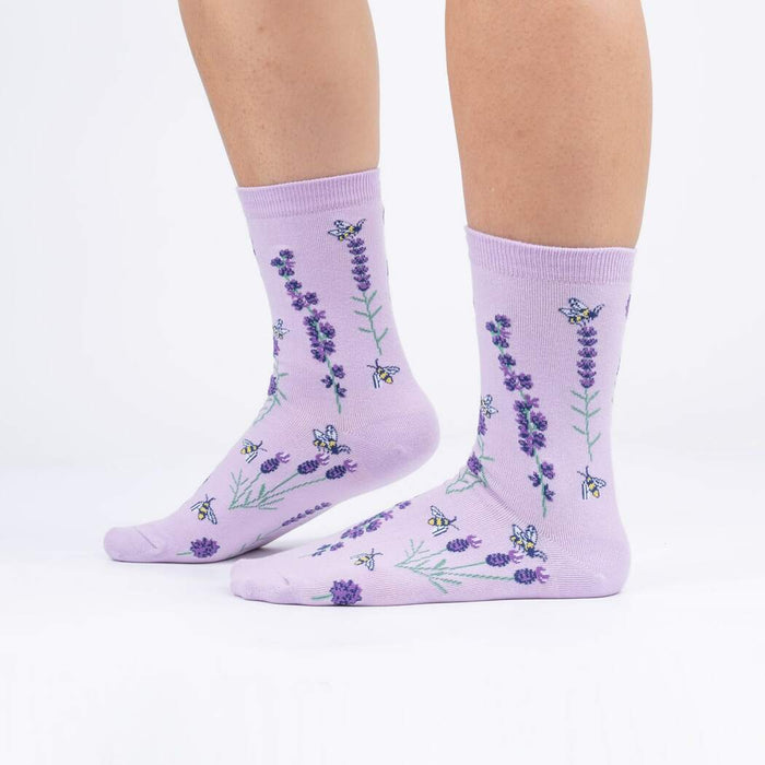 A pair of lavender crew socks with a pattern of purple flowers and yellow bees.